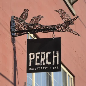 A square blade sign hanging from a unique arm